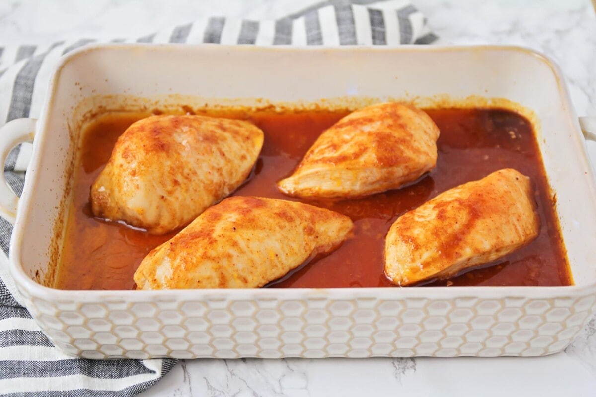 Chicken breasts covered in bbq sauce and baked in a dish.