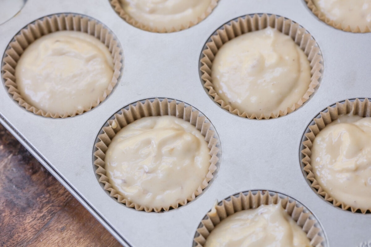Banana muffin batter scooped into liners in muffin tin.