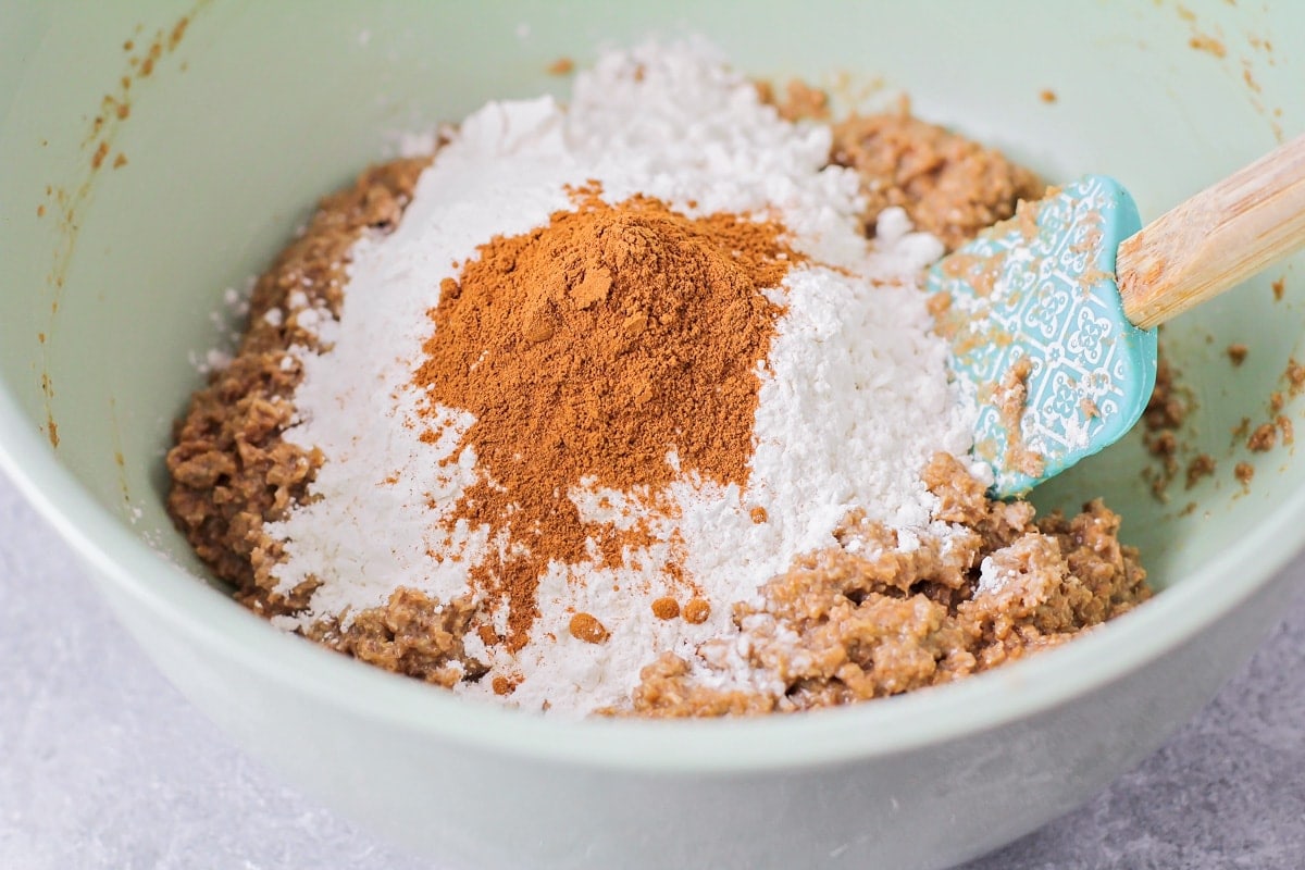 Combining wheat bran, flour, and cinnamon in a mint bowl.