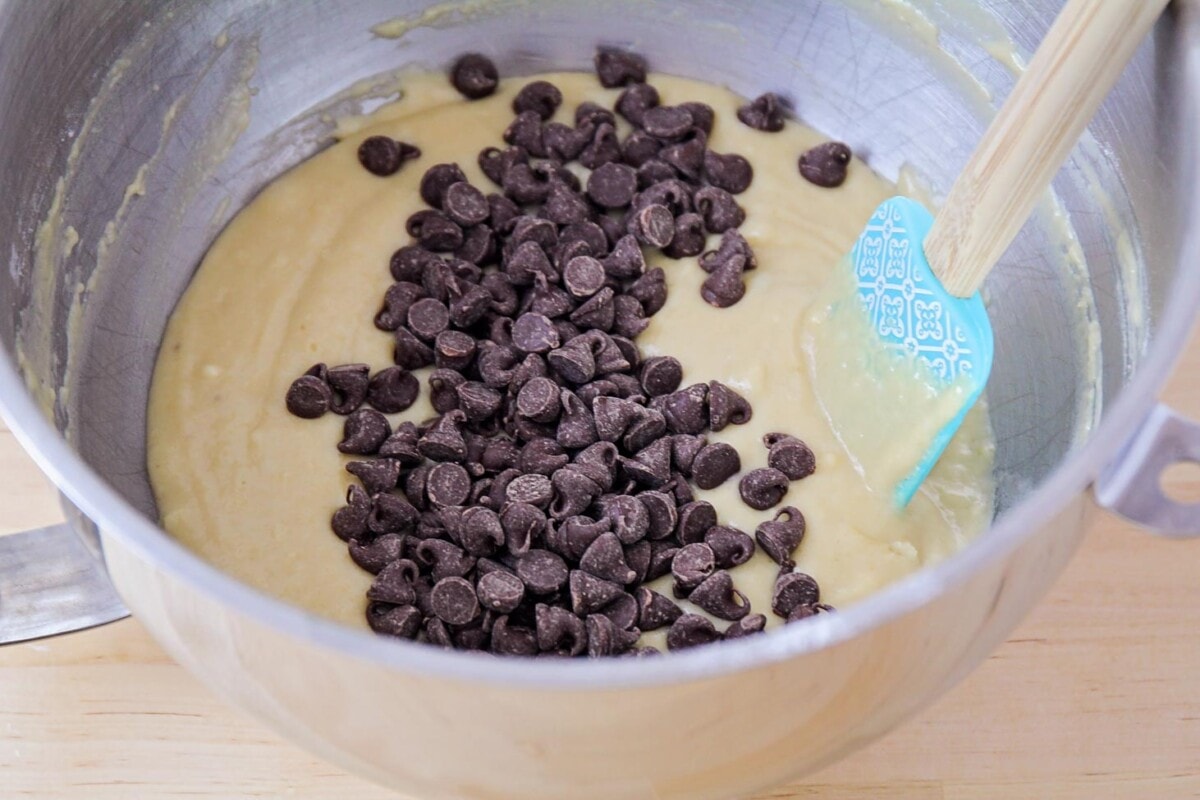 Mixing chocolate chips into the muffin batter.