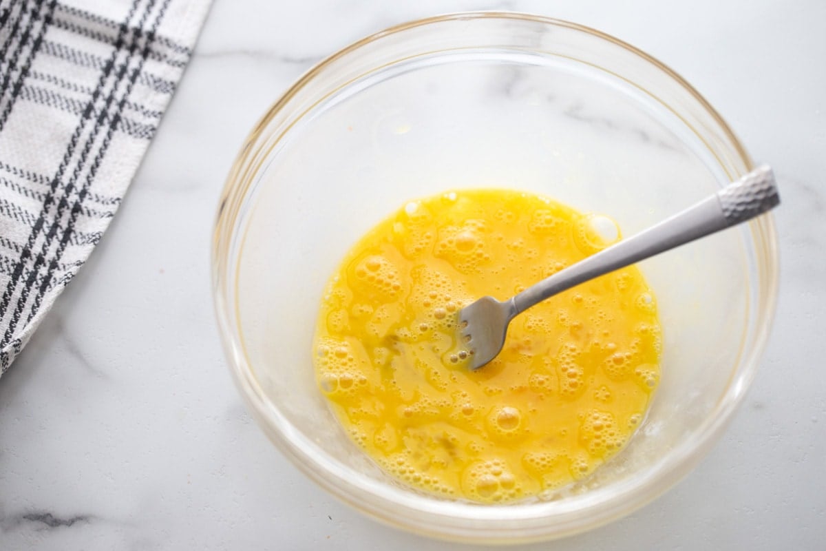 Eggs whisked together in a glass bowl.