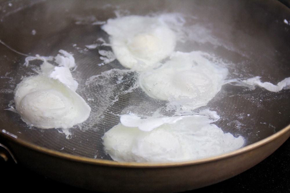 Poached eggs in a pan of simmering water.