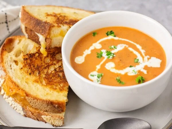 Homemade grilled cheese and tomato soup topped with fresh herbs.