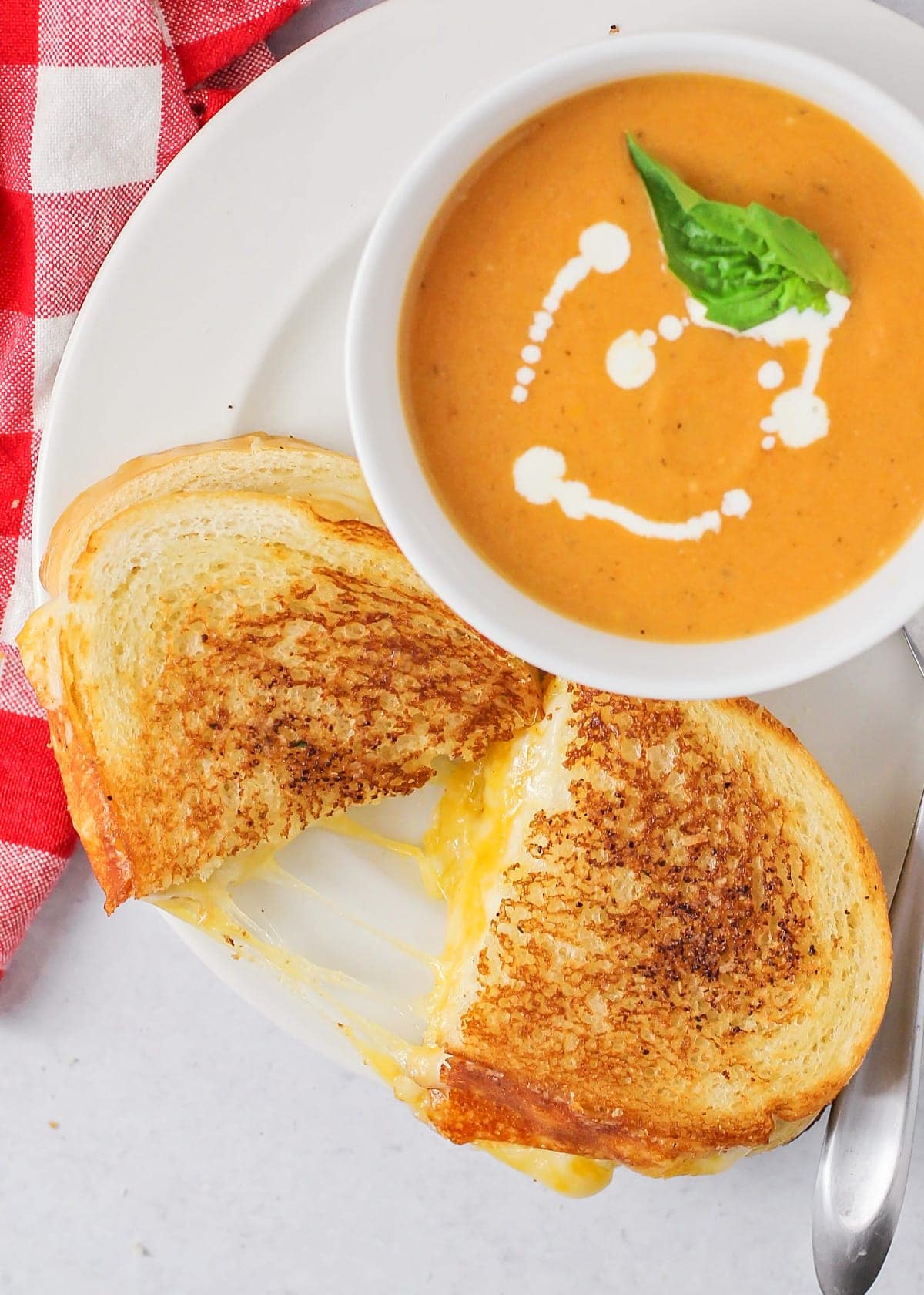 Best grilled cheese sandwich on a plate with a side of tomato soup.