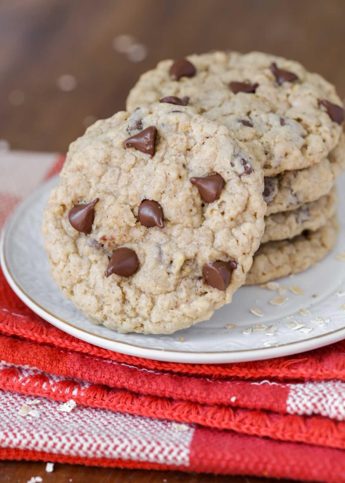 Chewy oatmeal chocolate chip cookies stacked on a white plate.