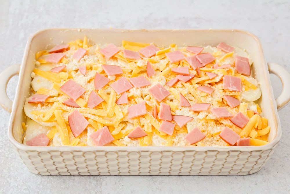 Scalloped potatoes and ham layered in a white baking dish.