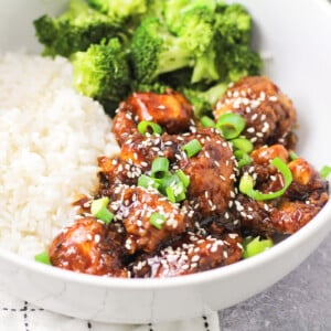 Sesame chicken served in a bowl with white rice.