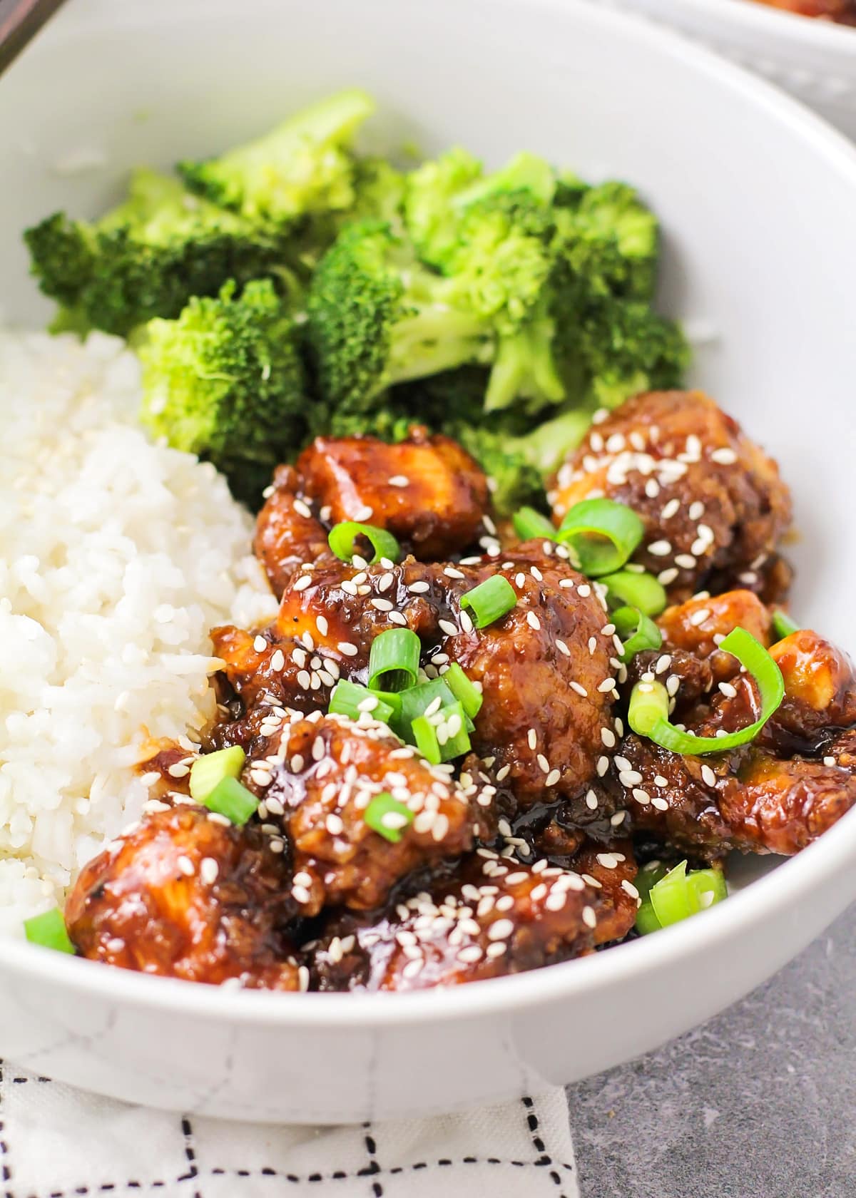 Close up image of Sesame Chicken recipe with sesame seeds and green onions over the top.