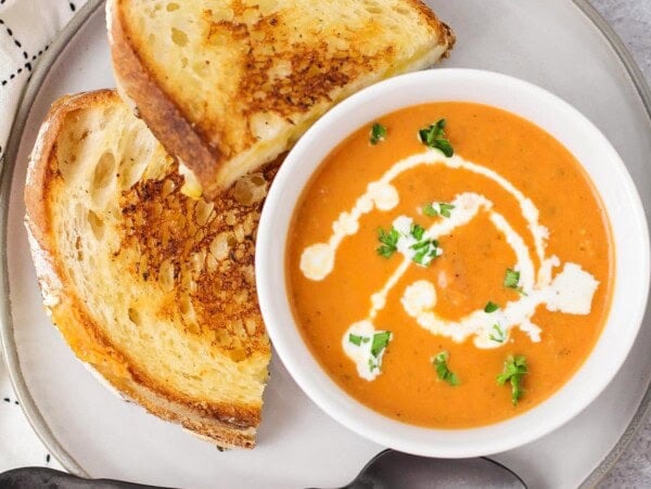 Creamy Tomato basil soup topped with fresh herbs and served with grilled cheese.