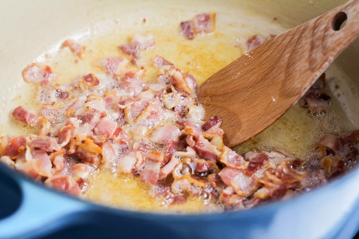 Bacon pieces cooking in a pot.