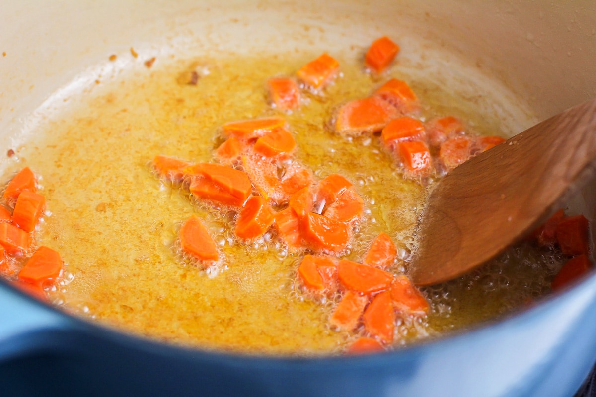 Cooking carrots in bacon grease in a pot.
