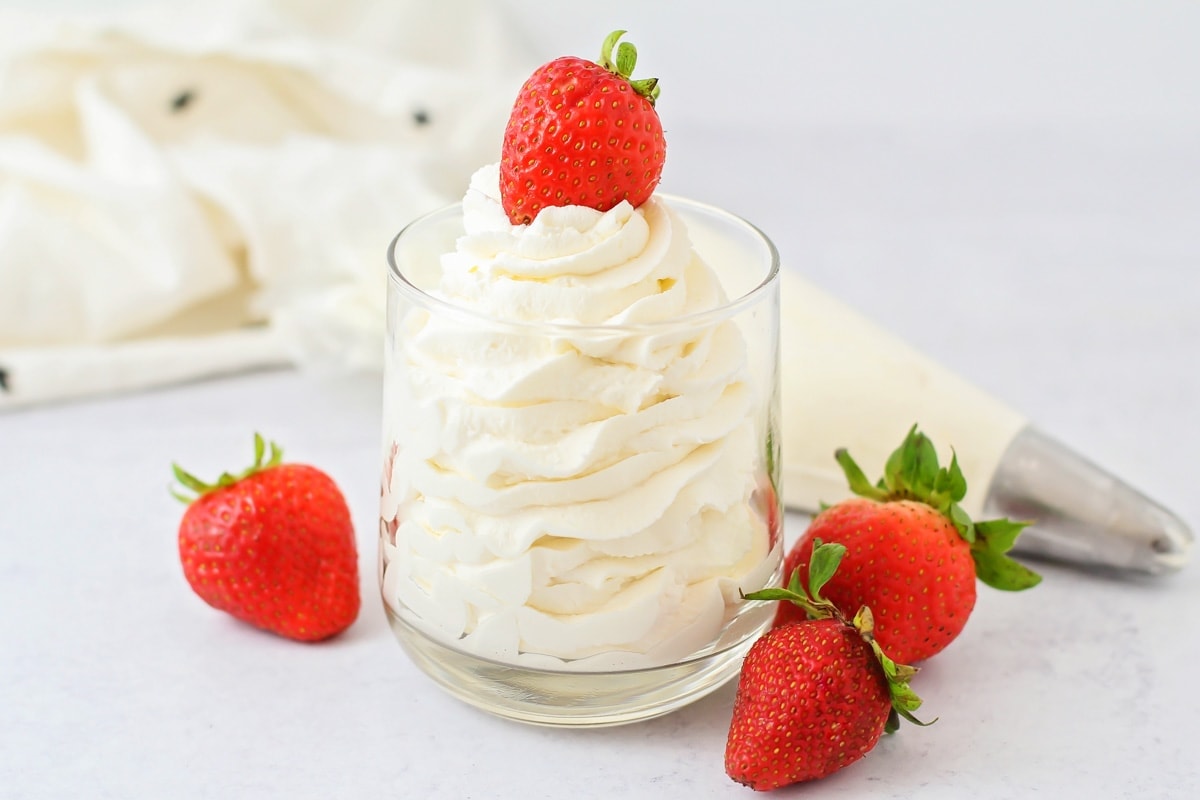 A cup filled with whipped cream and served with strawberries.