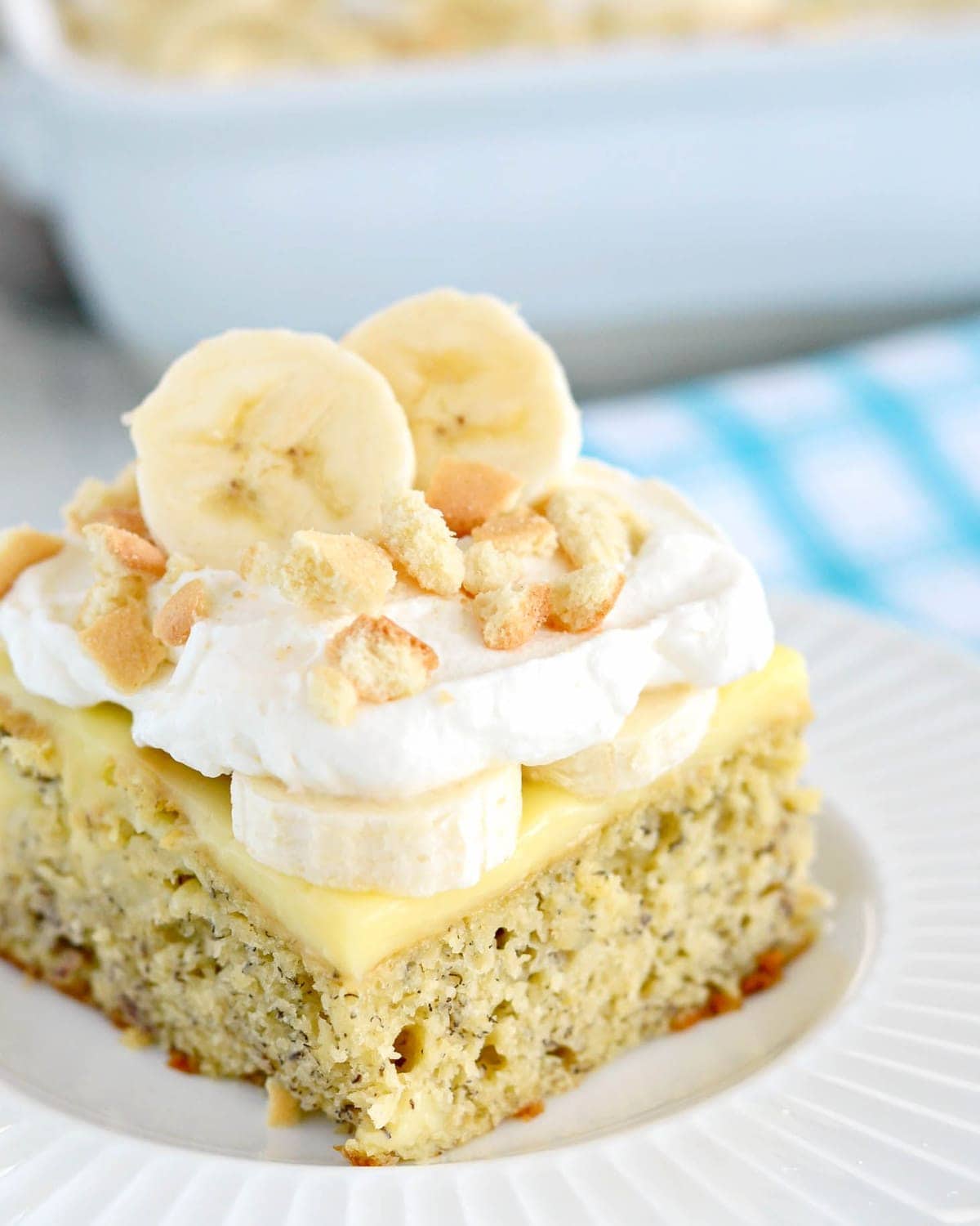 Banana Pudding Cake Recipe topped with whipped cream and fresh bananas.
