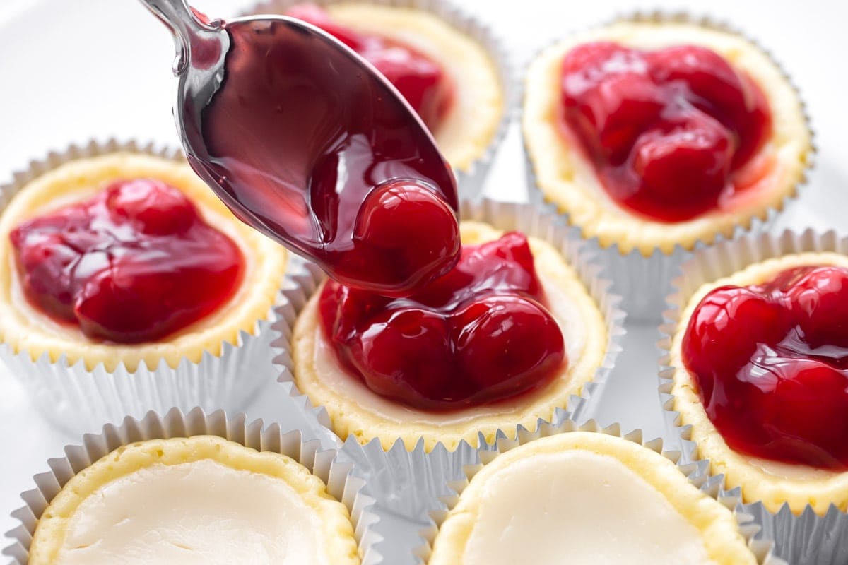 Topping cheesecake cupcakes with cherry filling topping.
