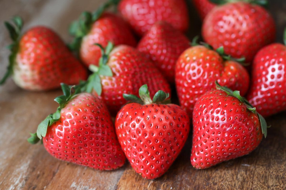 Clean strawberries on a wooden table.