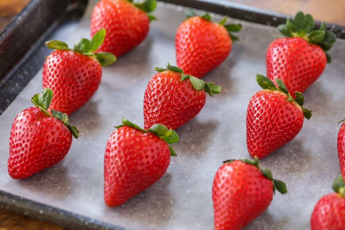 Strawberries on parchment paper lined baking sheet..