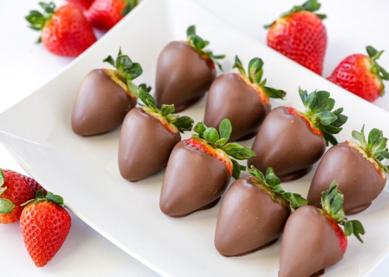 Chocolate covered strawberries recipe with berries on white plate.