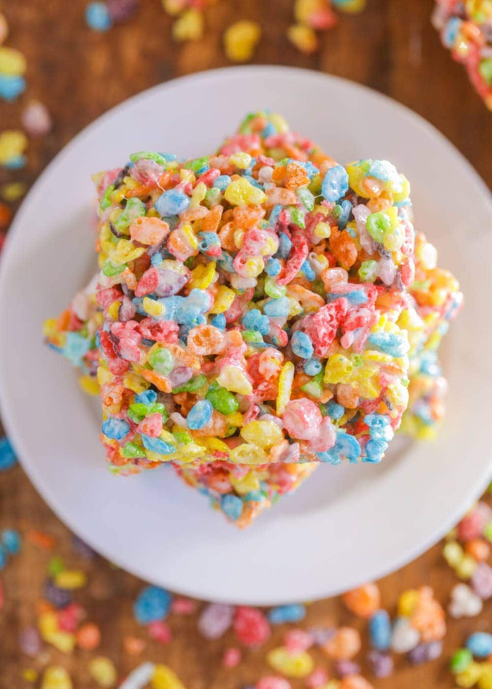 Fruity pebbles treats stacked on a white plate.