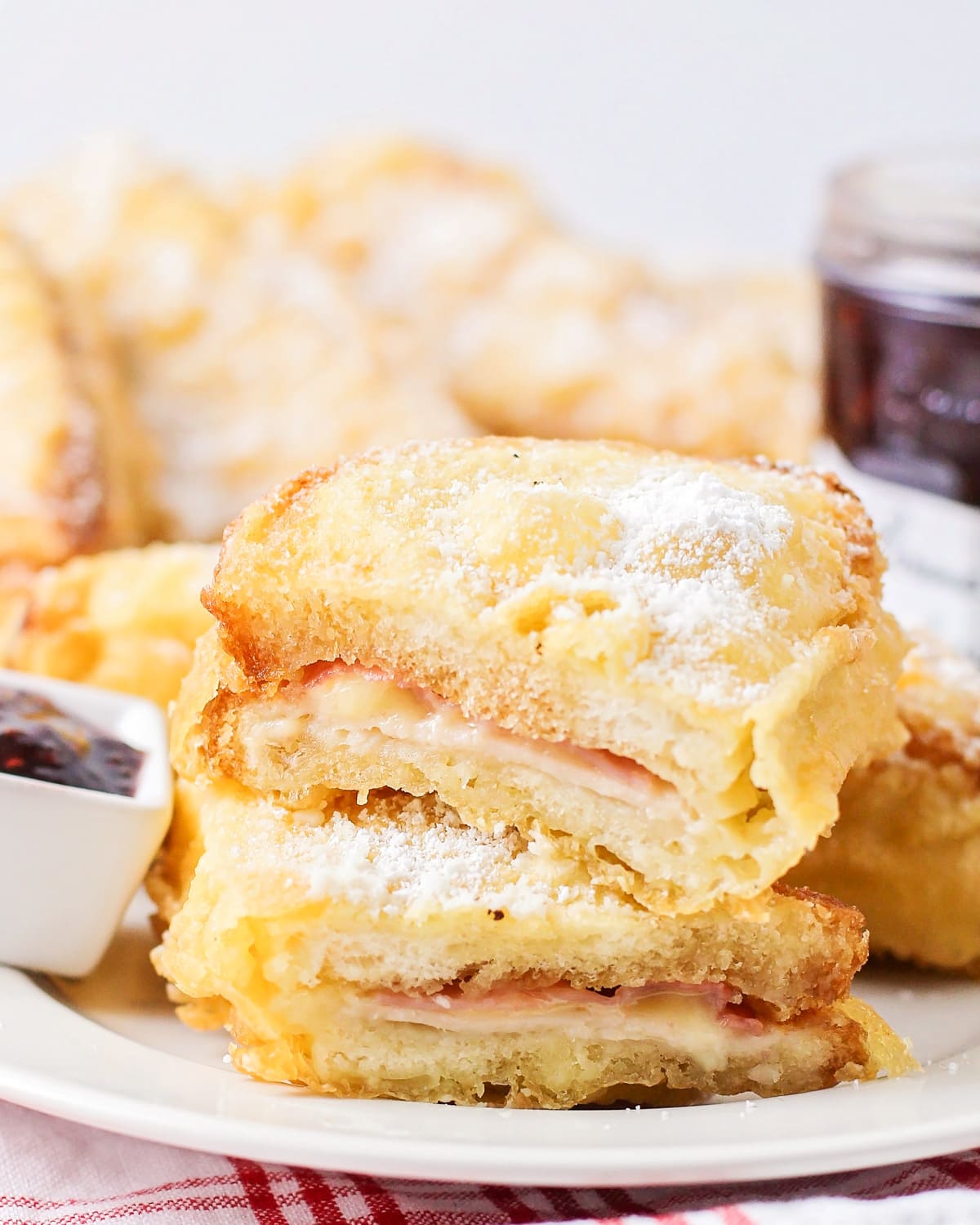 Monte cristo sandwich cut in half and stacked on top of each other on white plate.