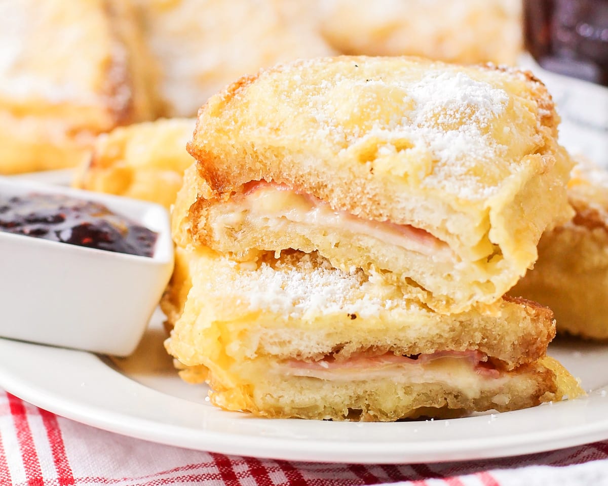 Monte cristo sandwich cut in half and stacked on a white plate.