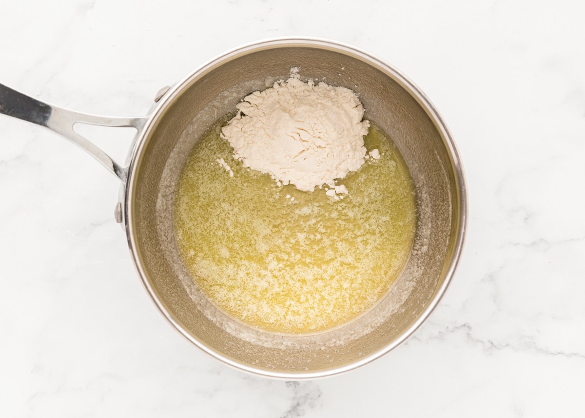 Adding flour to melted butter in a pot.