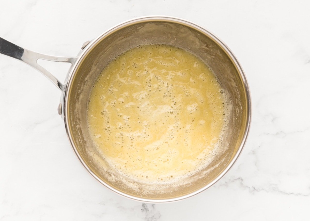 Whisking melted butter and flour in a pot.