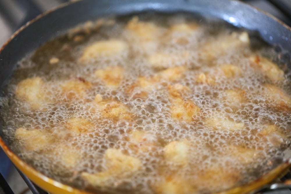 Chicken pieces frying in oil to make sweet and sour chicken recipe.