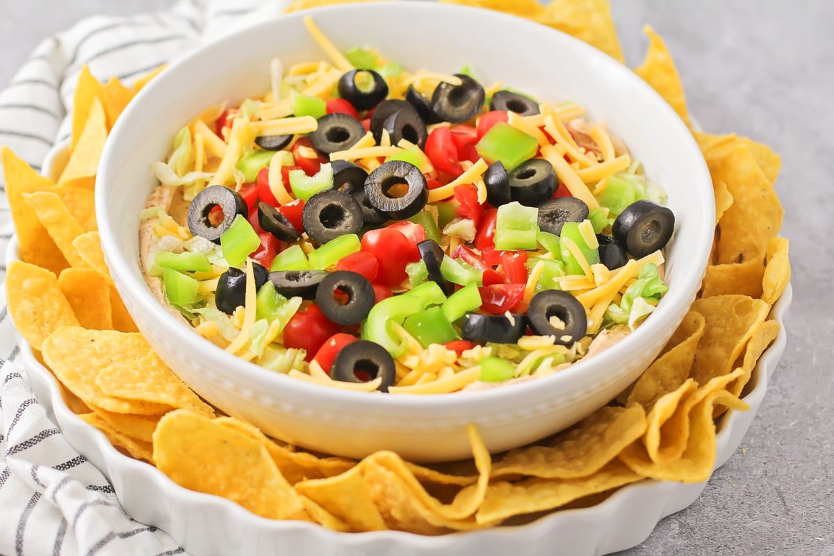 Taco Dip recipe in a white serving dish with tortilla chips.