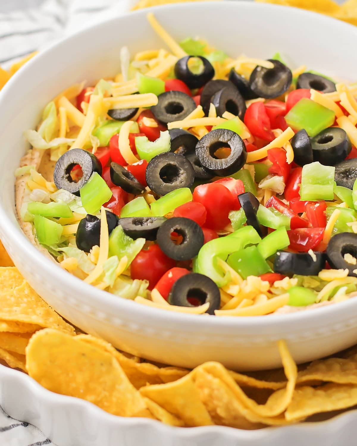 Close up of a bowl of taco dip recipe served with tortilla chips.