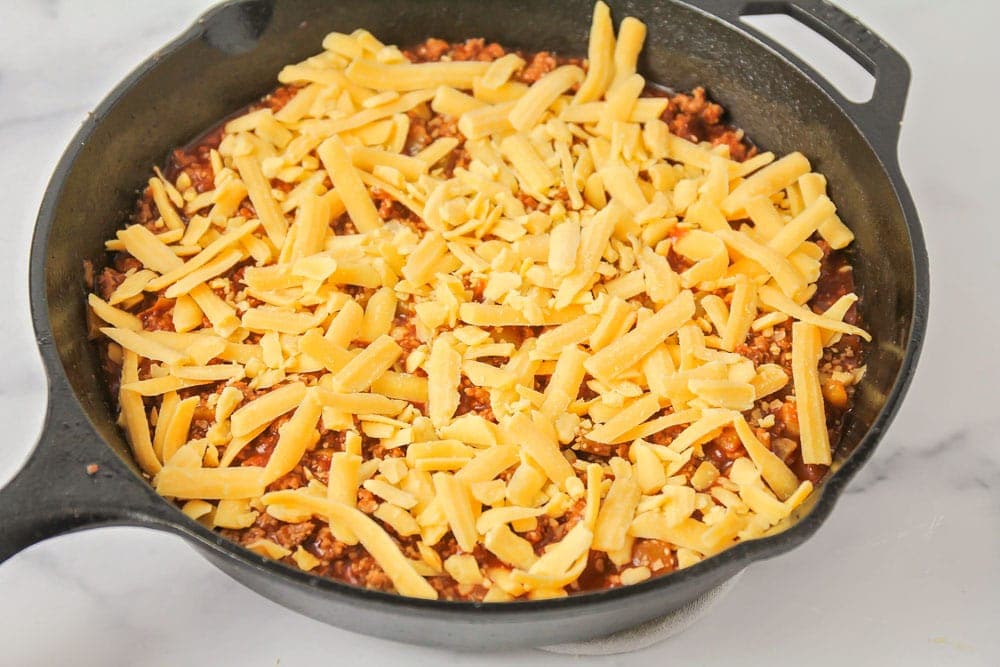 Shredded cheese layered on top of tamale pie meat mixture.