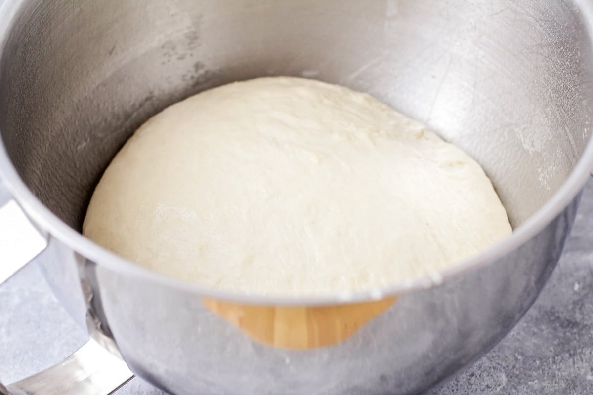 Bread dough rising in a metal bowl.