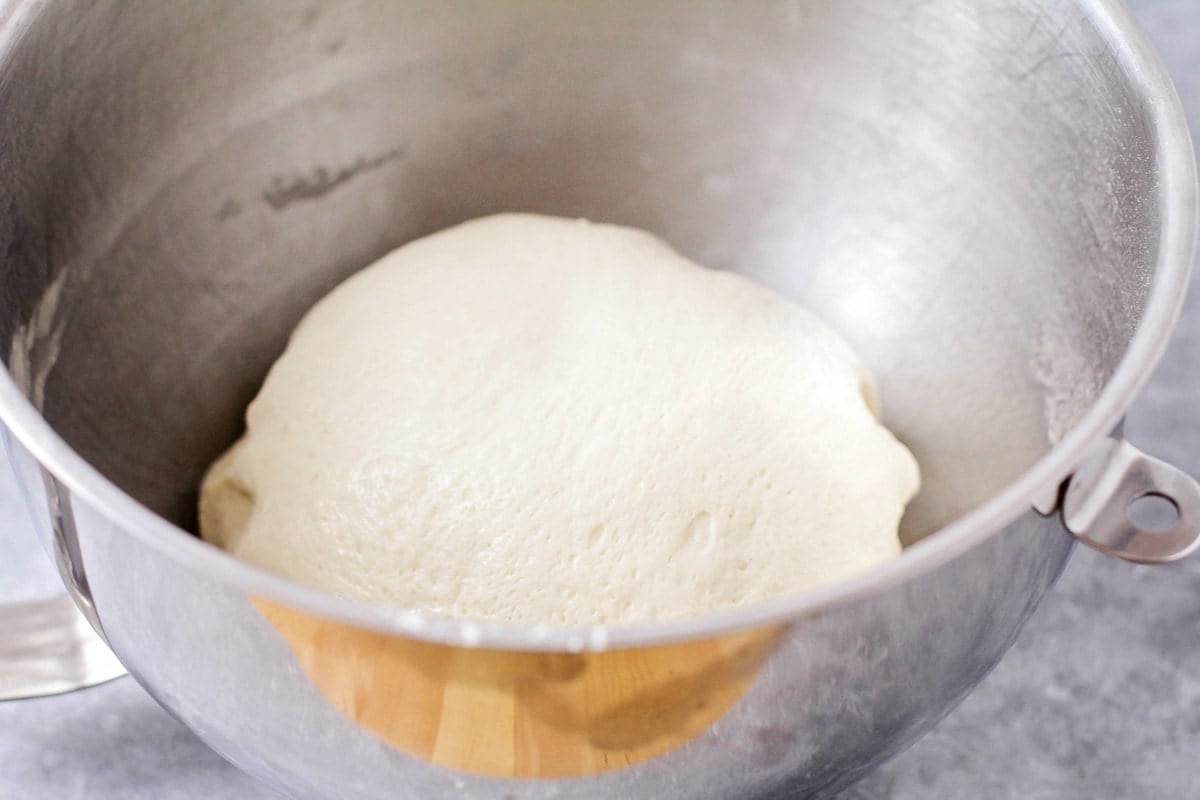 Bread dough rising in a metal bowl.