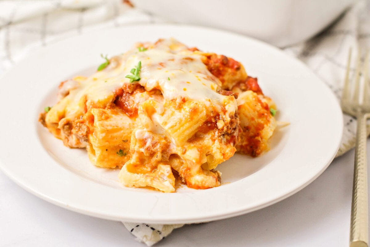 Deliciously cheesy baked rigatoni is meaty and hearty, a perfect family-style dish for any night of the week! A white plate filled with baked rigatoni.
