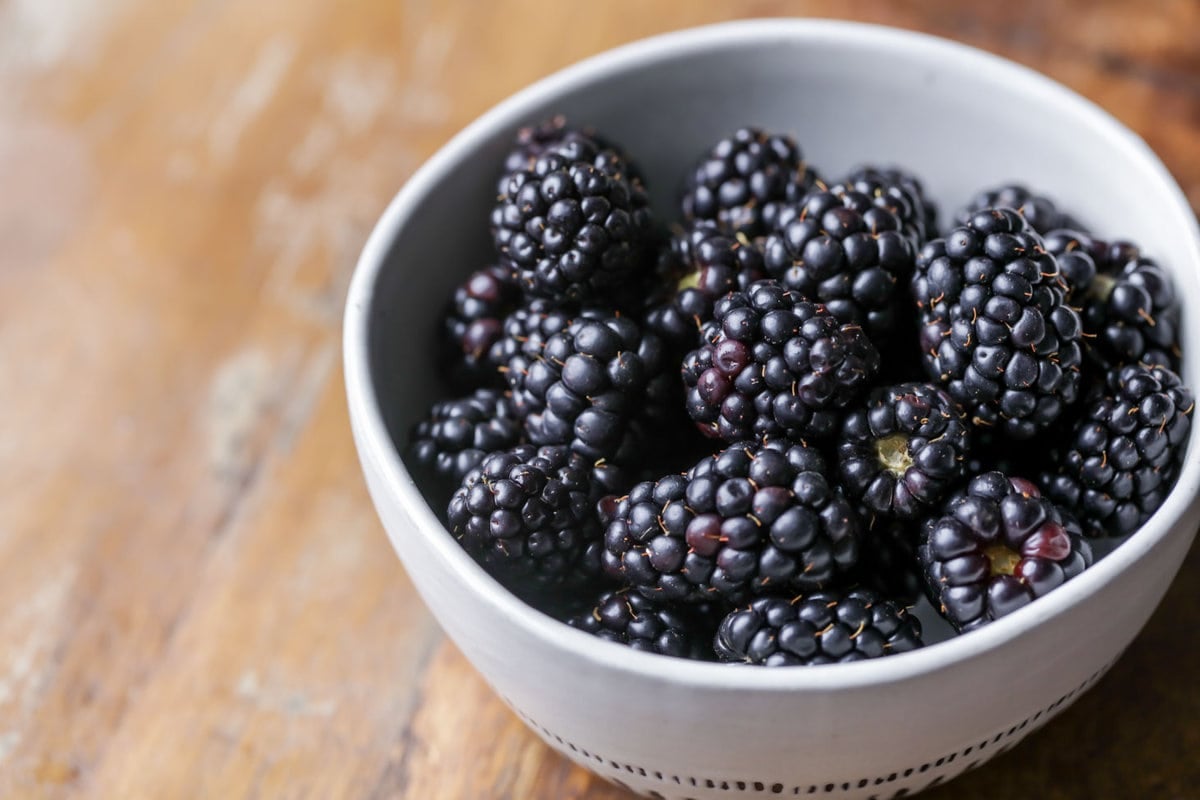 A white bowl of blackberries.