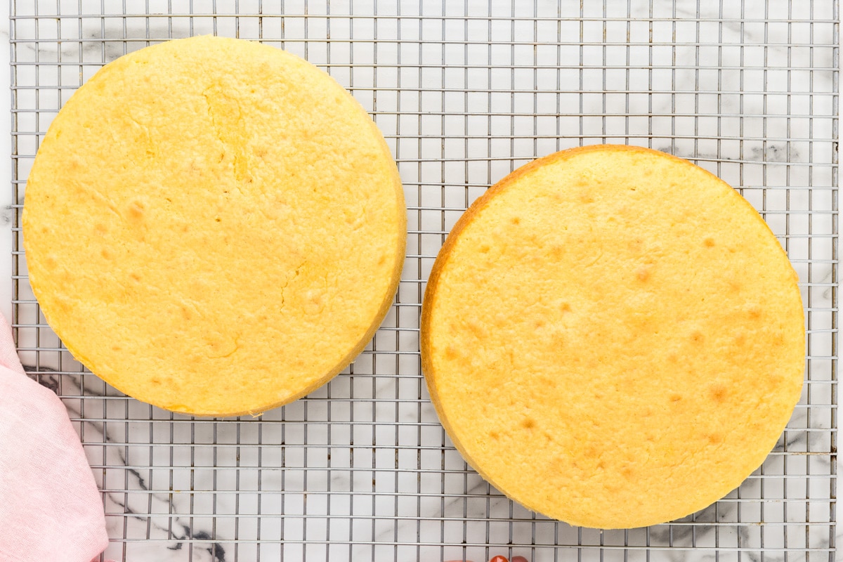 Two round cakes cooling on a rack.