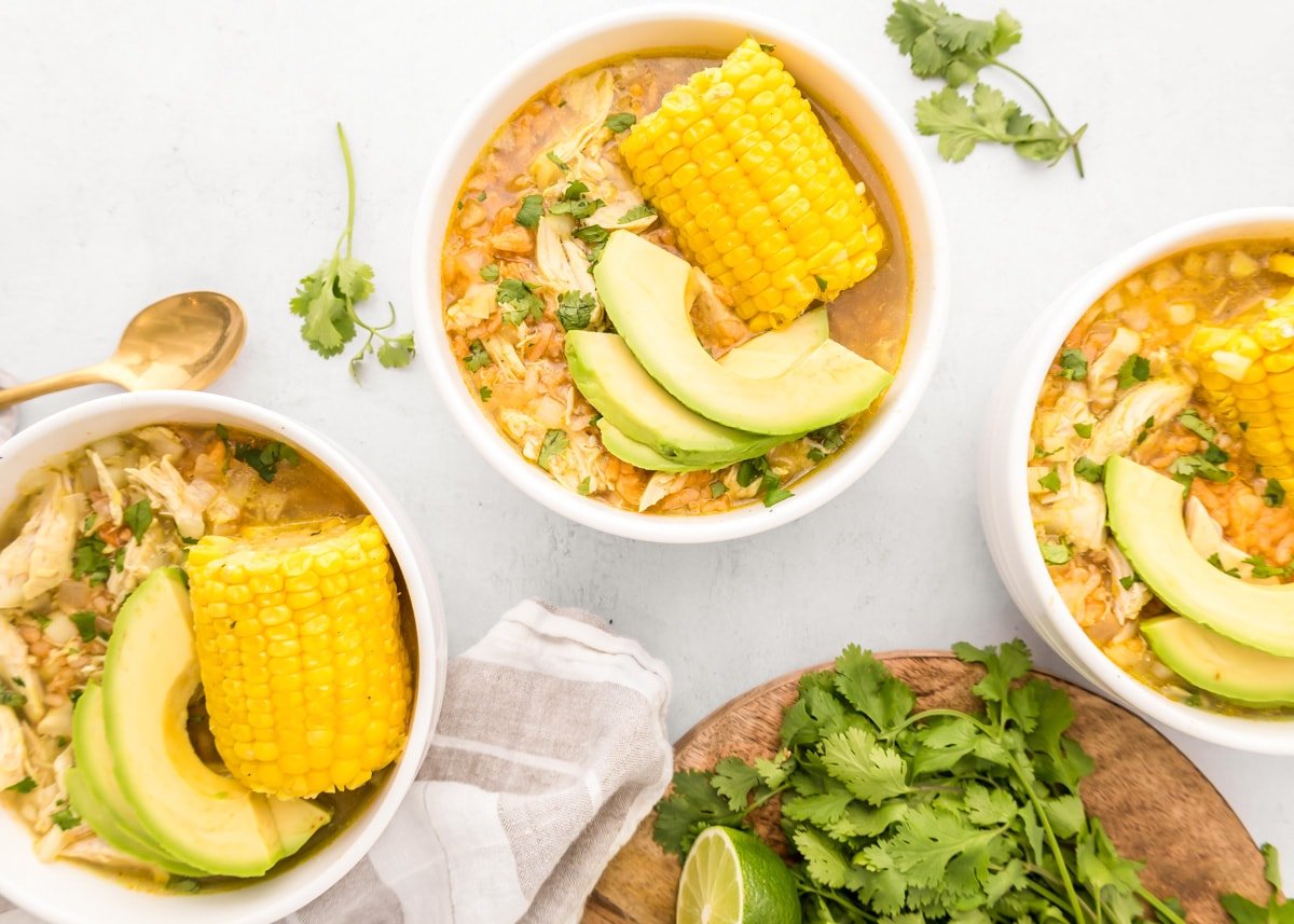 Several bowls of caldo de pollo on a kitchen counter.