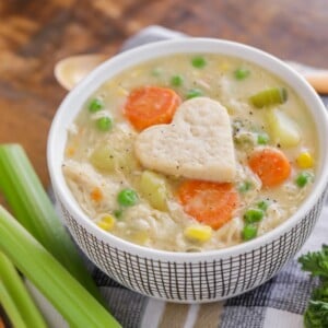 A bowl of chicken pot pie soup topped with a heart pie crust.
