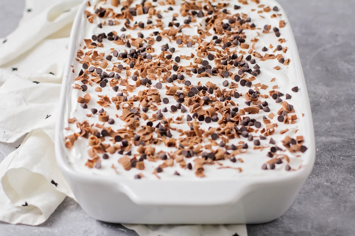Sprinkling chocolate chips and shavings on to the top of a whipped cream layer.