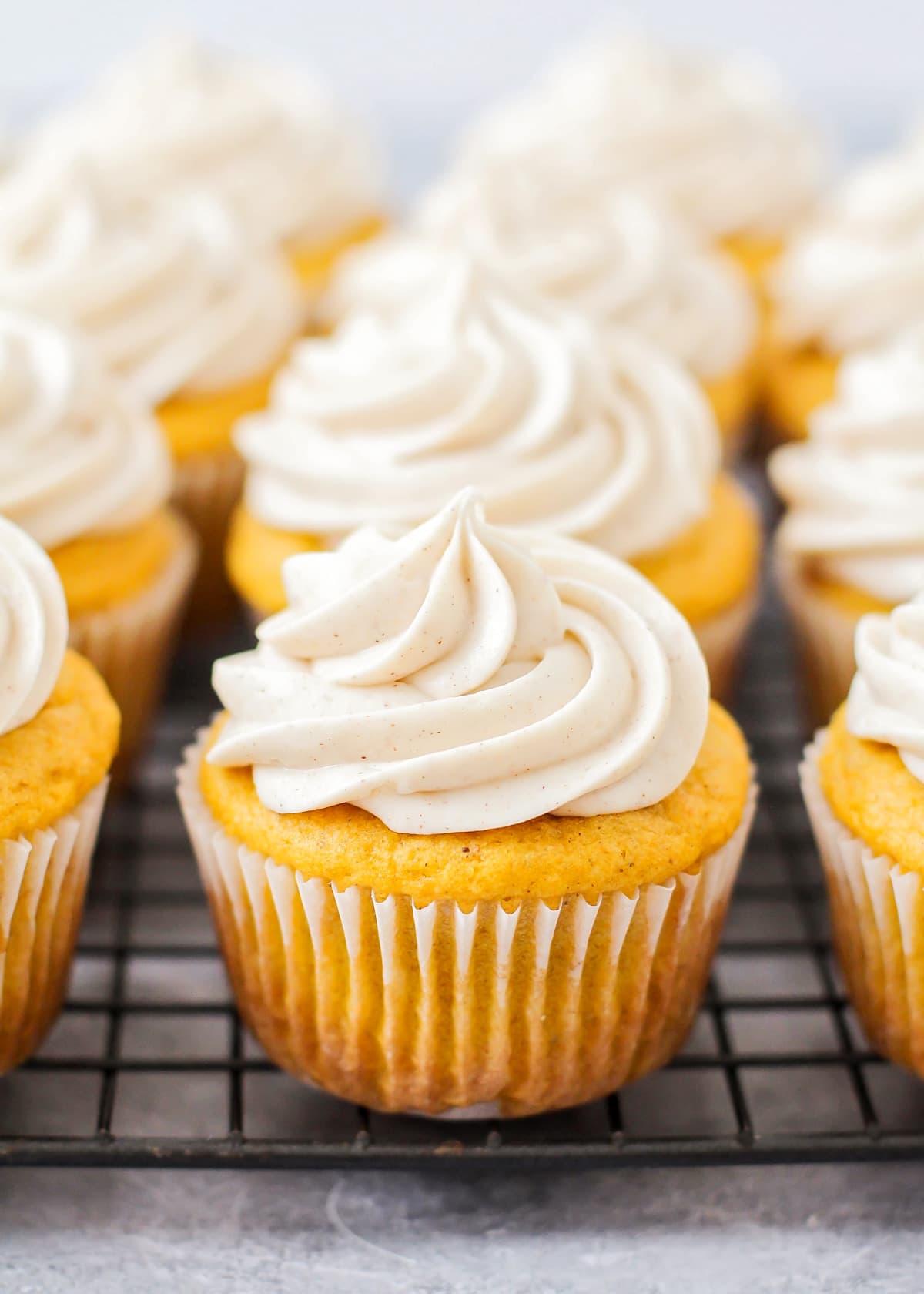 Close up of several banana cupcakes topped with cinnamon cream cheese frosting.