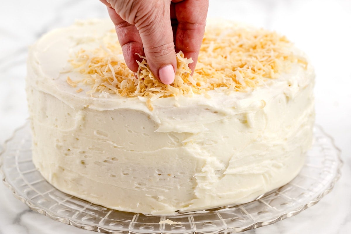 Topping a frosted cake with toasted coconut.