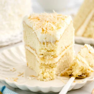 A slice of layered coconut cake on a white plate.