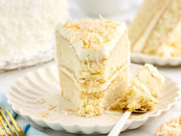 A slice of layered coconut cake on a white plate.
