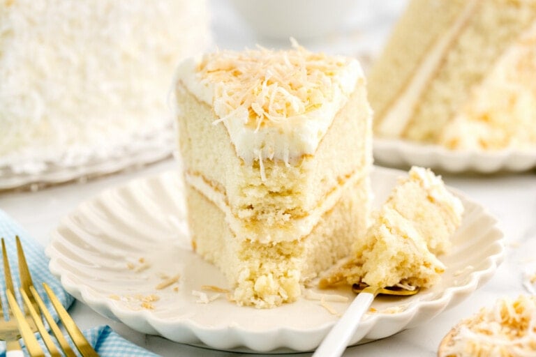 A slice of layered coconut cake on a white plate.