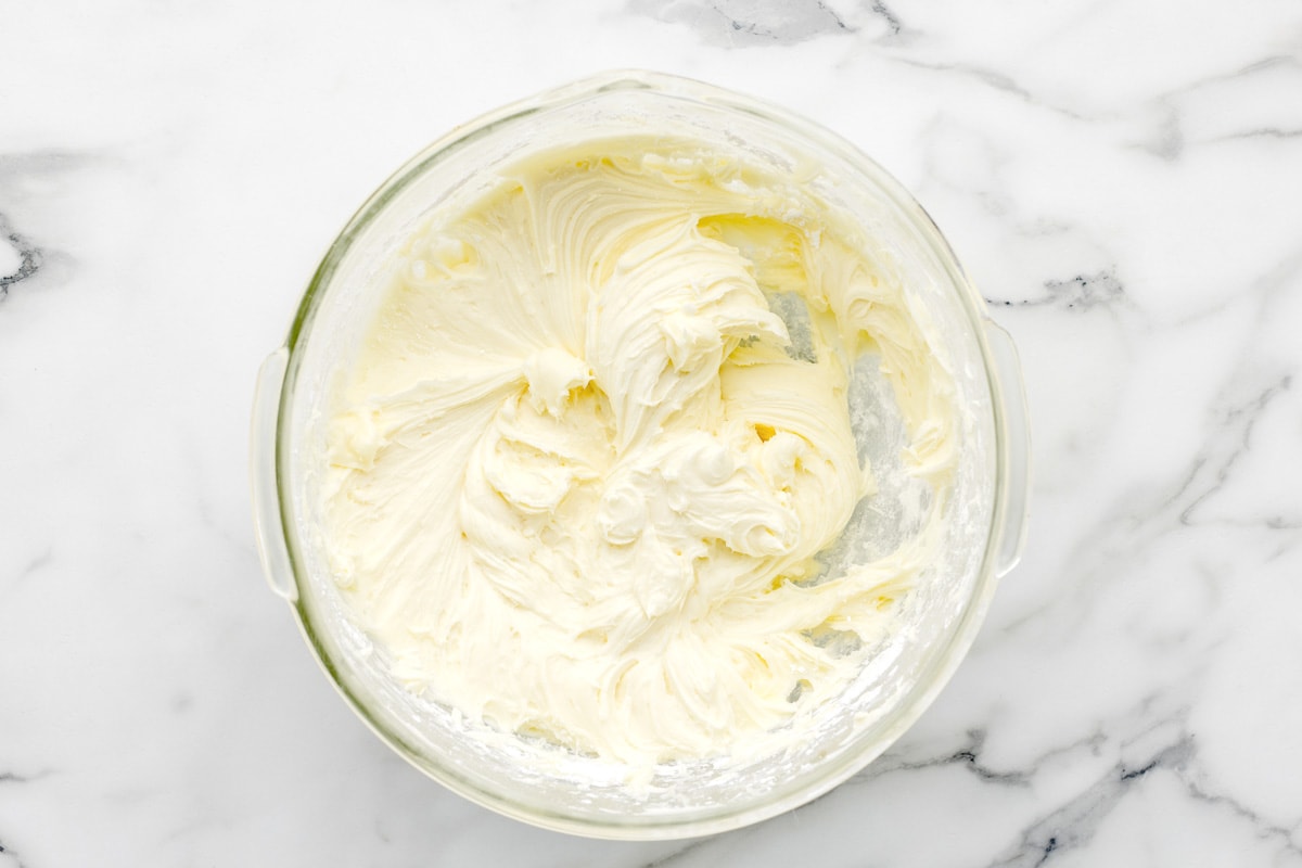 Whipping cream cheese and butter in a glass bowl.