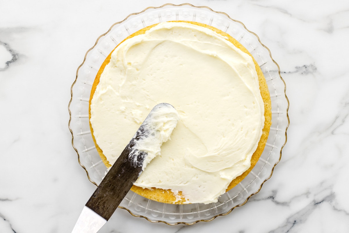 Spreading coconut cream cheese frosting on a cake.