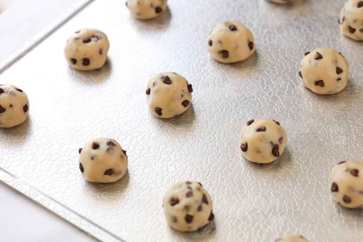 Balls of cookie dough on a metal baking sheet.