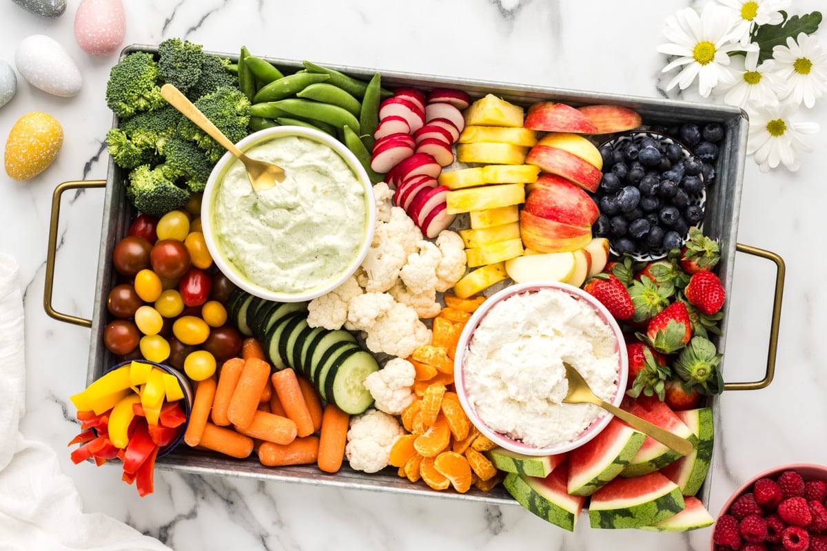 Top view of an Easter charcuterie board covered and fresh fruits, veggies, and dips.