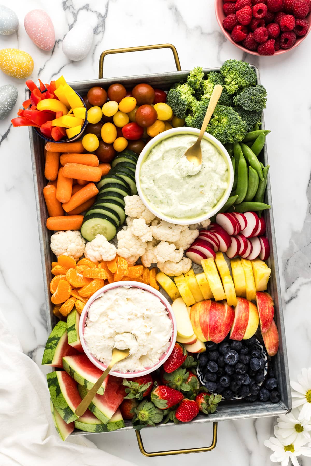 Top view of an Easter charcuterie board covered in fruits, veggies, and dips.