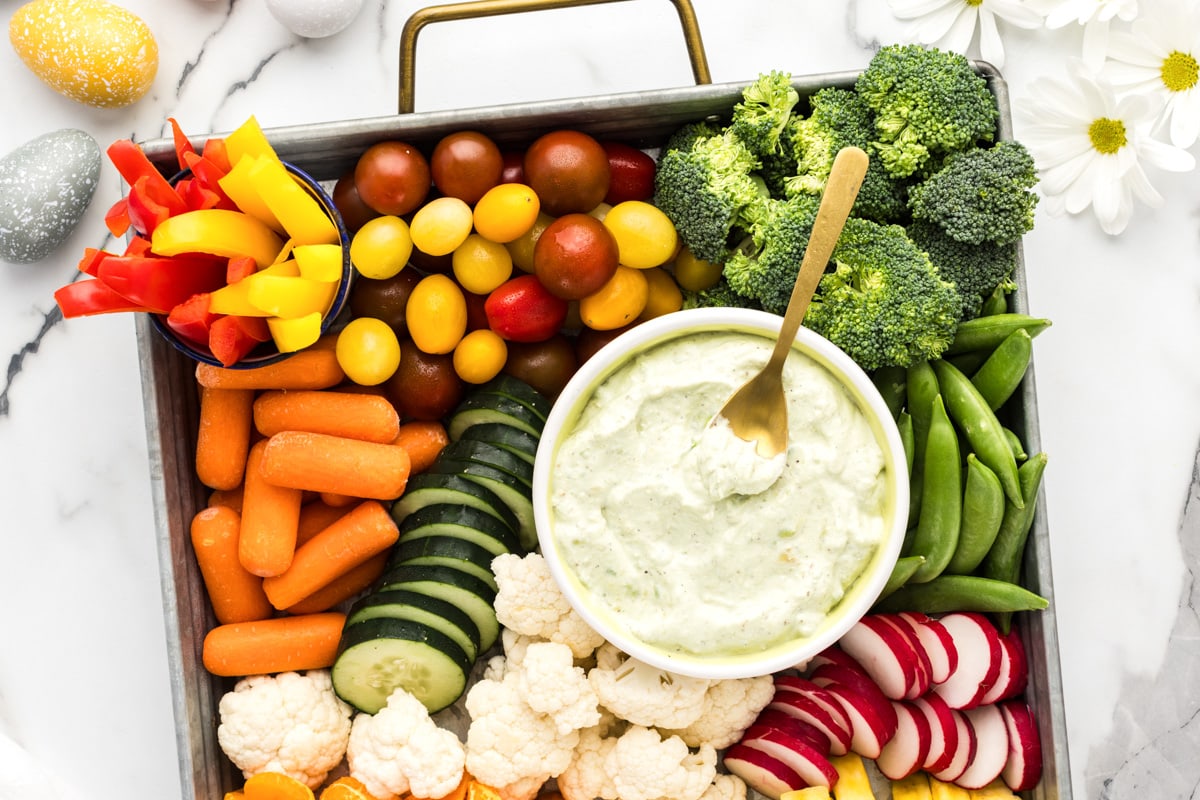 Close up of a bowl of veggie dip surrounded by cut veggies.