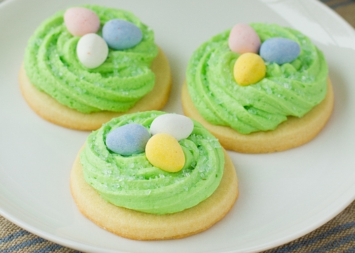 Easter sugar cookies decorated like birds nests on a white plate.